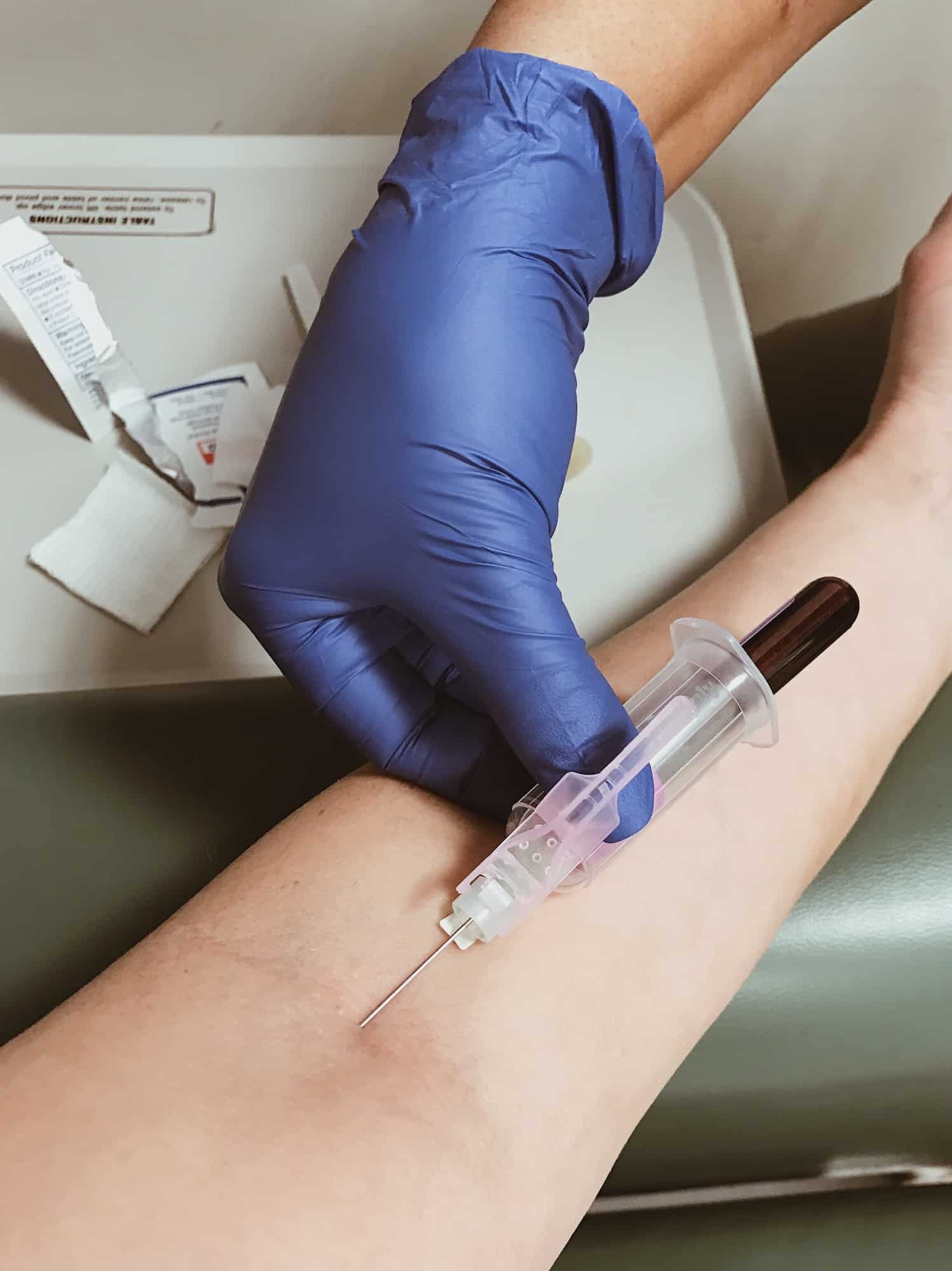 A blue gloved medical nurse is drawing a blood sample for a patient’s health analysis