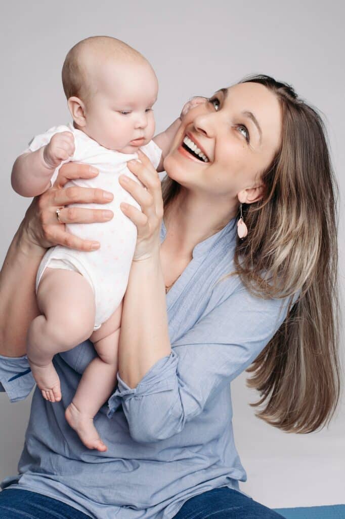 Beautiful young mother holds the child on her hands and looks happy