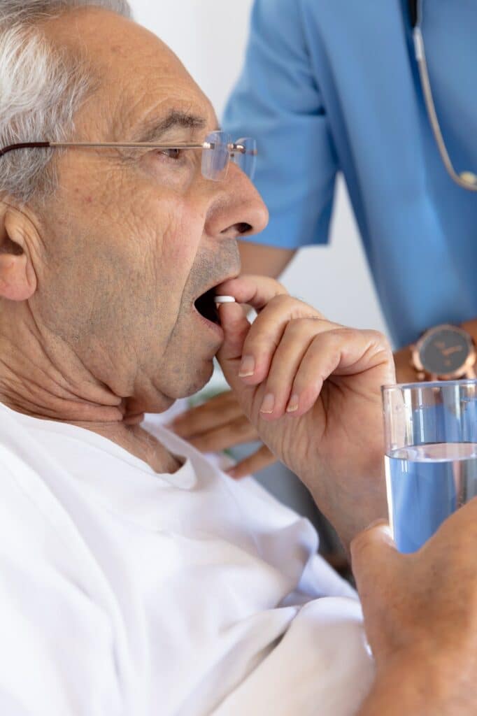 Caucasian senior man eating medical pills lying on the bed at home