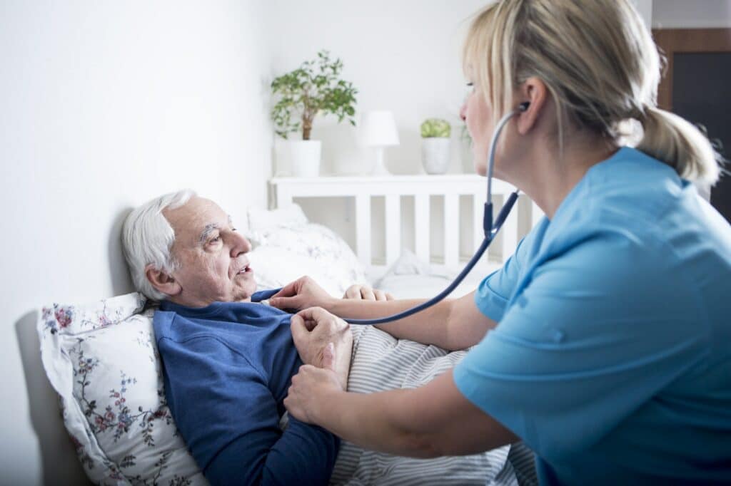 Gereatric nurse using stethoscope on patient