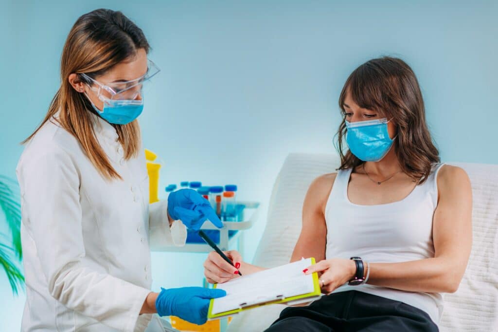 Nurse with Protective Mask Filling in Information Form. Blood Drawing and Analysis
