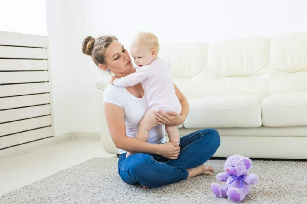 Young happy loving mother and her baby daughter is playing. Maternal care. Childcare